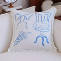 Decorative pillow with blue line art on a white background, placed on a couch.